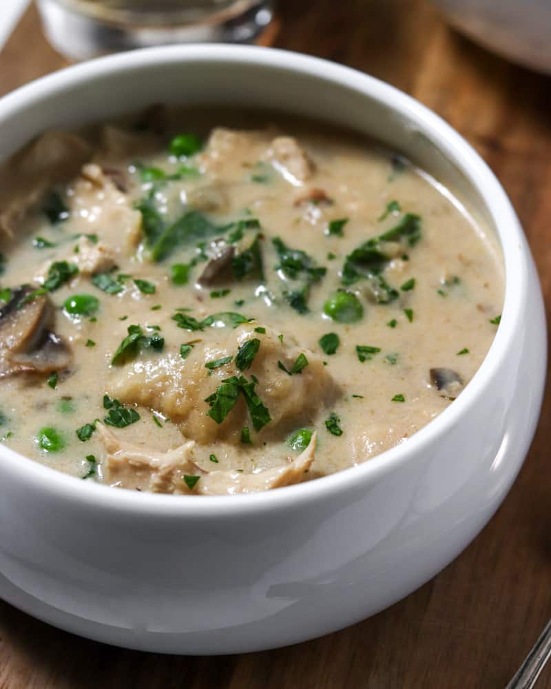 A bowl full of chicken and fluffy parmesan dumplings in rich, creamy broth