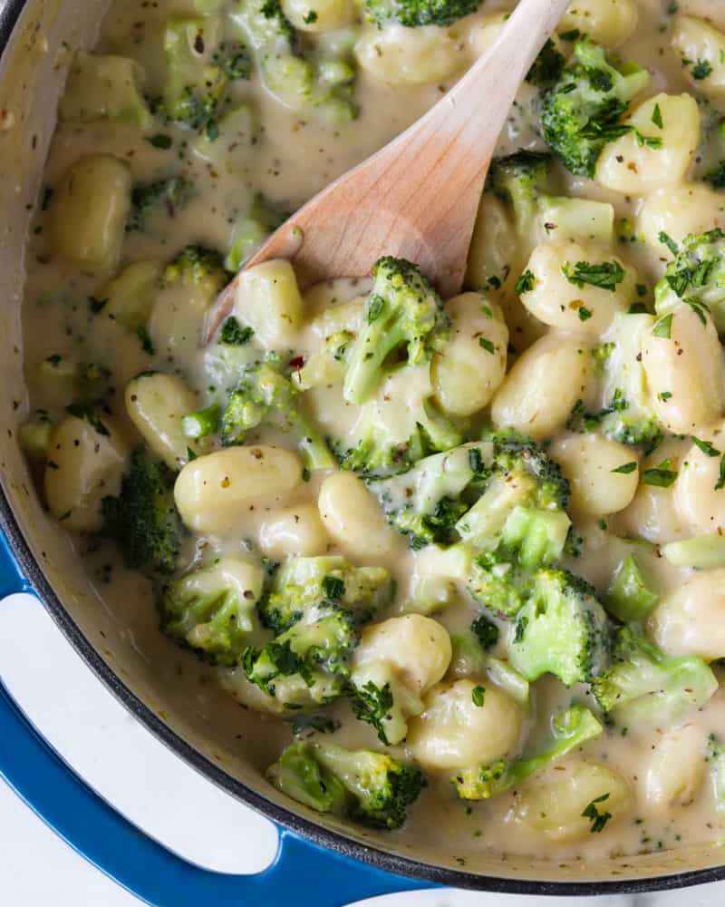 A spoon scooping out creamy parmesan garlic gnocchi from the pan