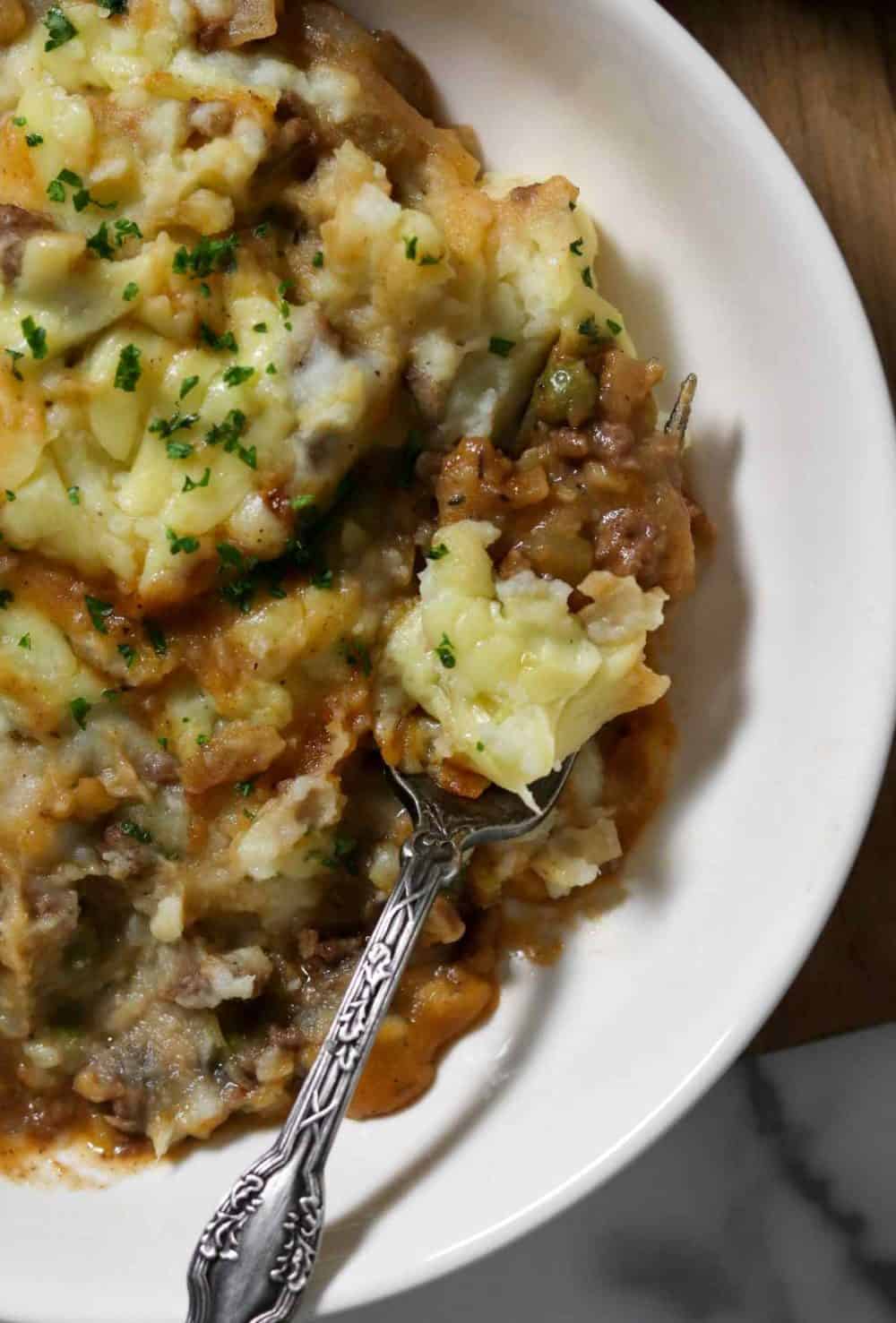 A fork full of savory shepherd's pie topped with cheesy mashed potatoes