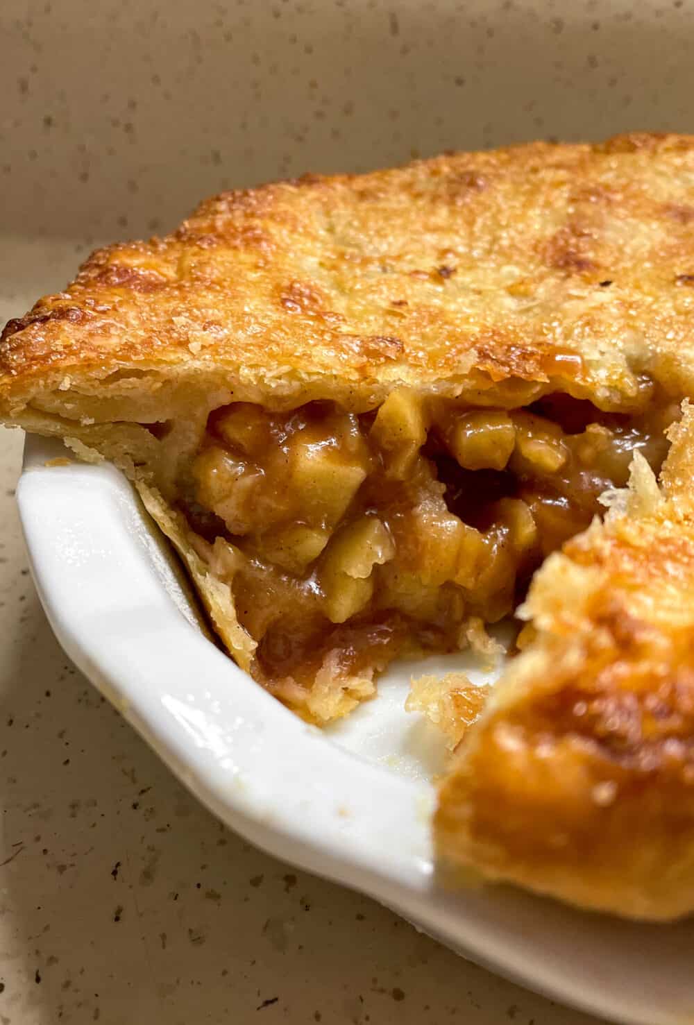 An apple pie with a slice taken out, revealing the sweet, spiced apple filling inside