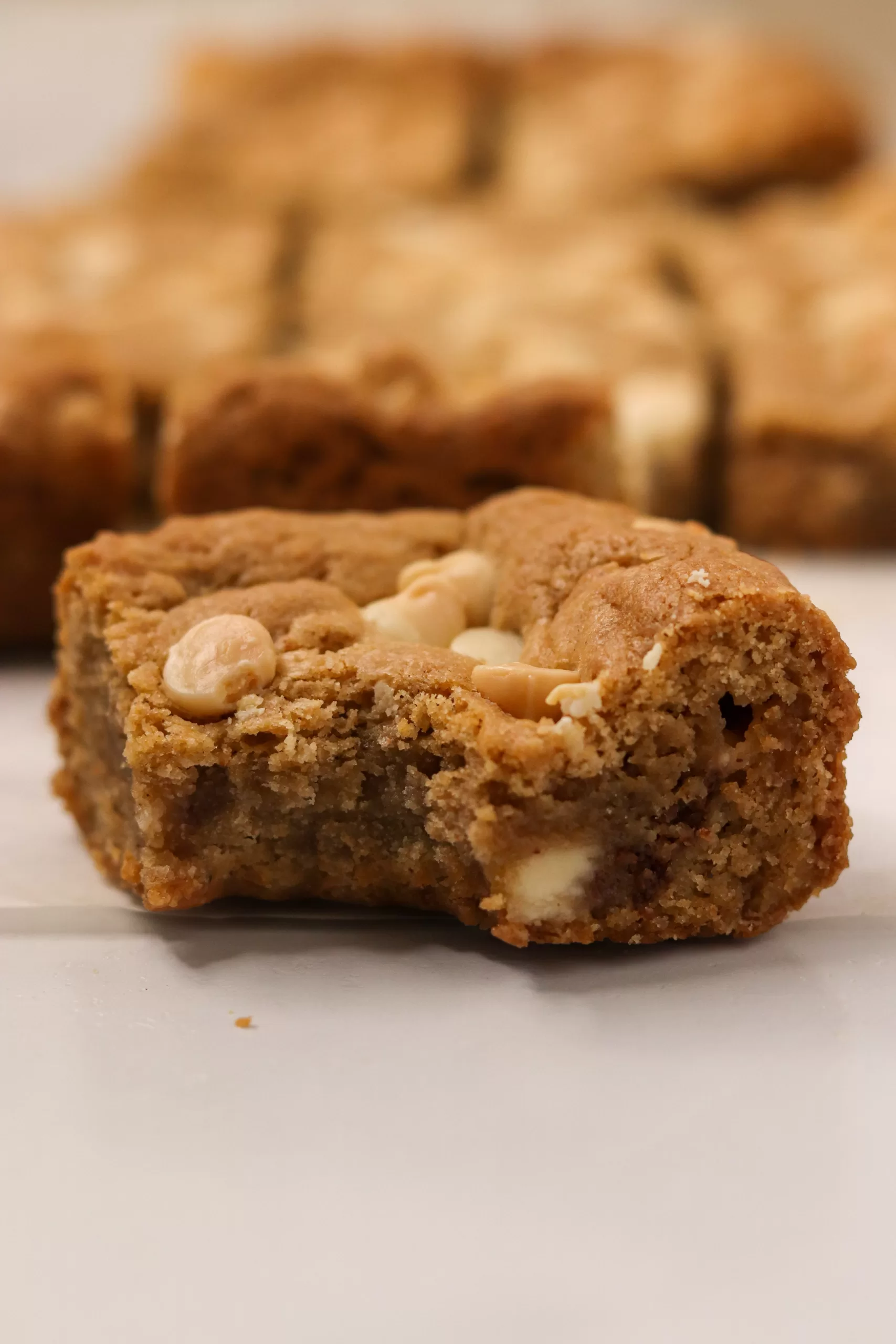 A white chocolate eggnog cookie bar with a bite taken out of it to show the chewy texture.